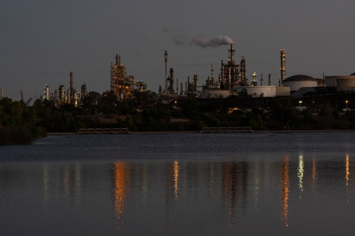 Lights from the Phillips 66 Los Angeles Refinery Wilmington Plant are reflected in the water at dusk.