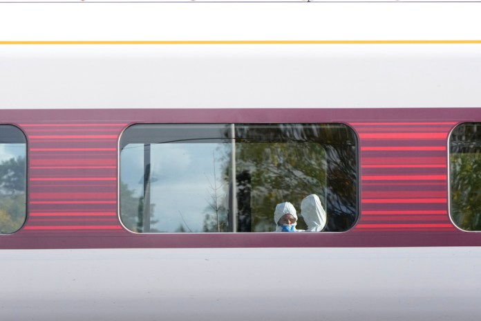 Forensic investigators through the window of a train.