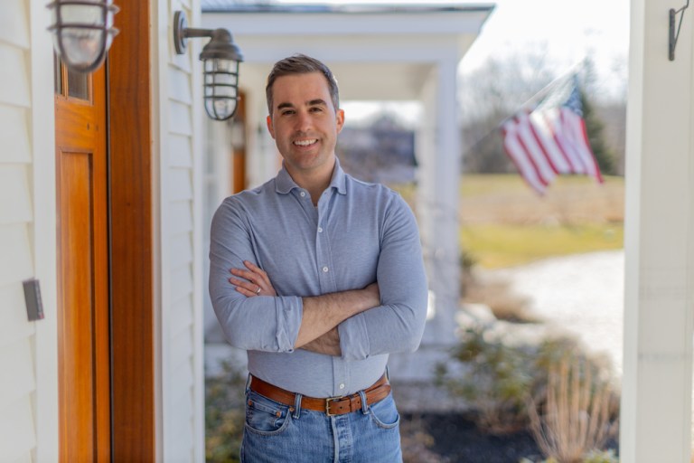 Maine Democrat Jordan Wood stands on a porch.