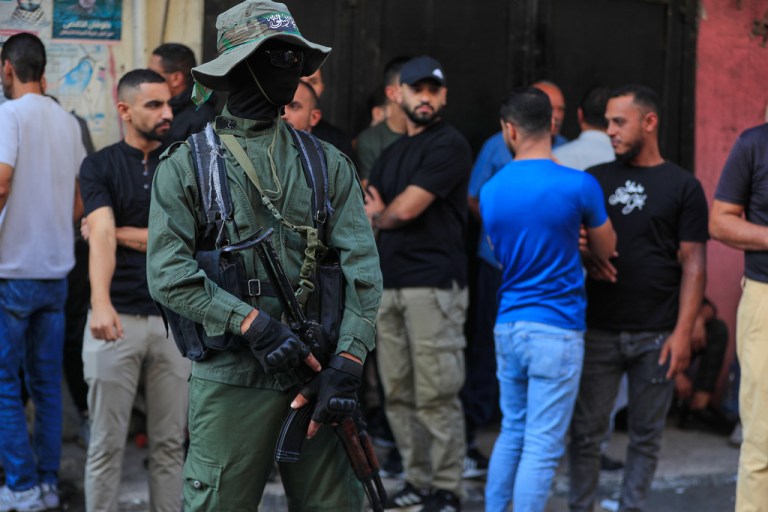 A Hamas fighter stands guard during the funeral procession of the victims of an Israeli airstrike.