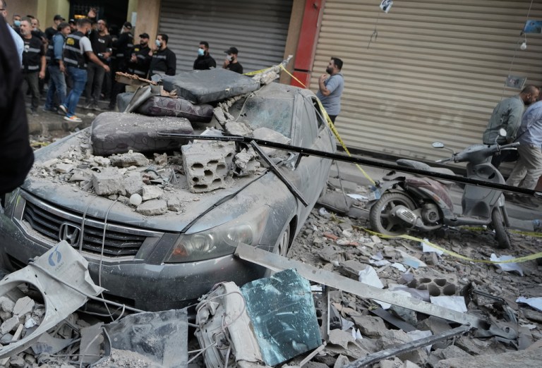 Security officers gather near destroyed vehicles at the site where an Israeli strike hit at an apartment building in Dahiyeh, a southern suburb of Beirut, Sunday, Nov. 23, 2025.