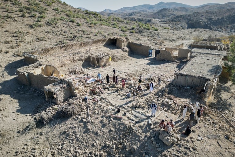 Afghan men search through rubble.