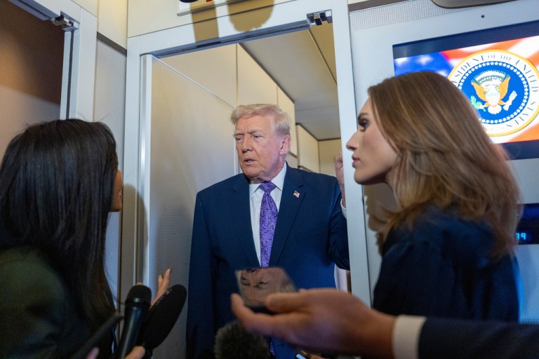 President Donald Trump speaks with reporters while in flight on Air Force One.