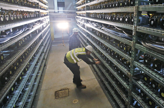 Workers look over racks of bitcoin data miners during construction of a bitcoin data center in Virginia Beach, Virginia, in 2018. (Steve Helber/AP)