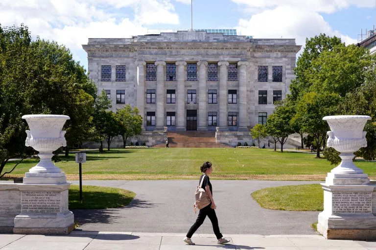 A person walks in front of the Harvard Medical School.
