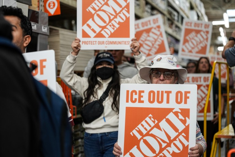 Protesters hold signs as they march through a Home Depot.