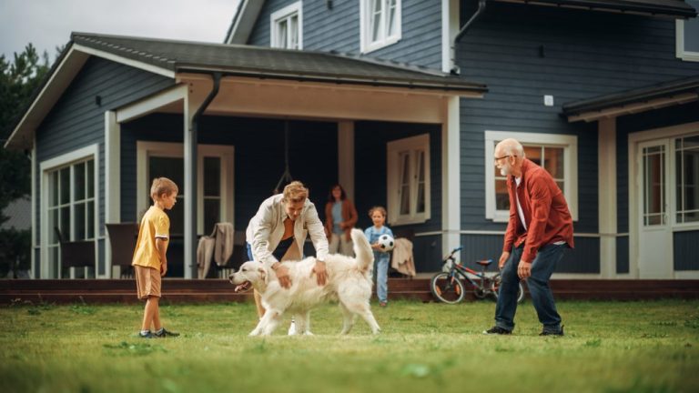 Family members spending leisure time in their front yard. Grandfather playing ball with his son and grandchildren outside with kids and pet dog.