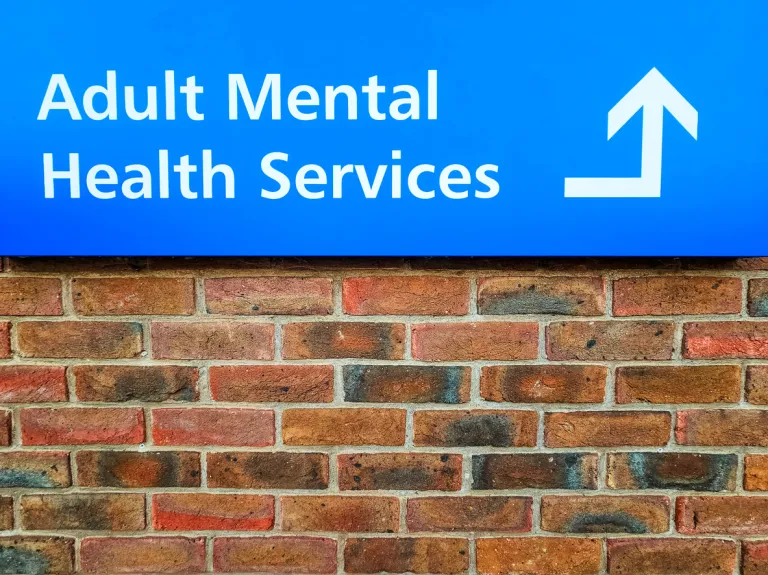 A sign saying 'Adult Mental Health Services' outside a support facility.