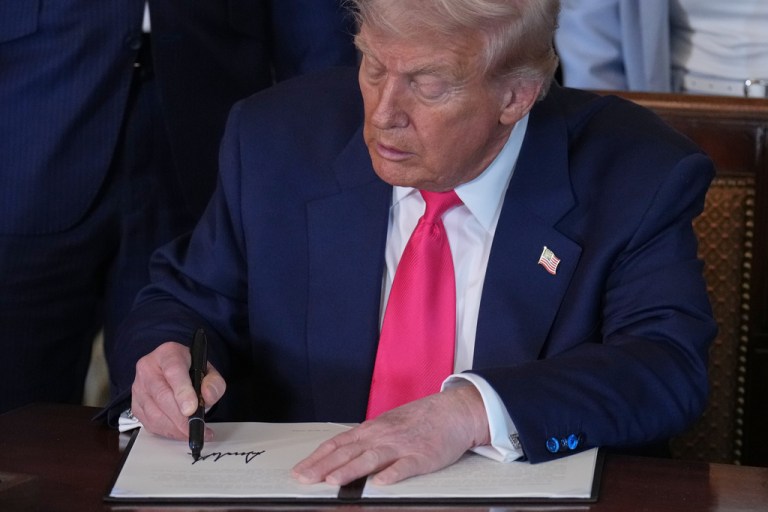 President Donald Trump signs an executive order during an event on foster care in the East Room of the White House.