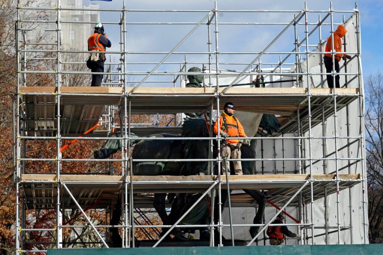 Workers from York Scaffold cover the scaffold surrounding the controversial equestrian statue of President Theodore Roosevelt, at the American Museum of Natural History, as it's prepared for removal, in New York, Friday, Dec. 3, 2021. The Theodore Roosevelt Presidential Library in Medora, ND, has agreed to take the bronze statue, which has been the subject of years of criticism. It depicts the former president on horseback with a Native American man and an African man flanking the horse.