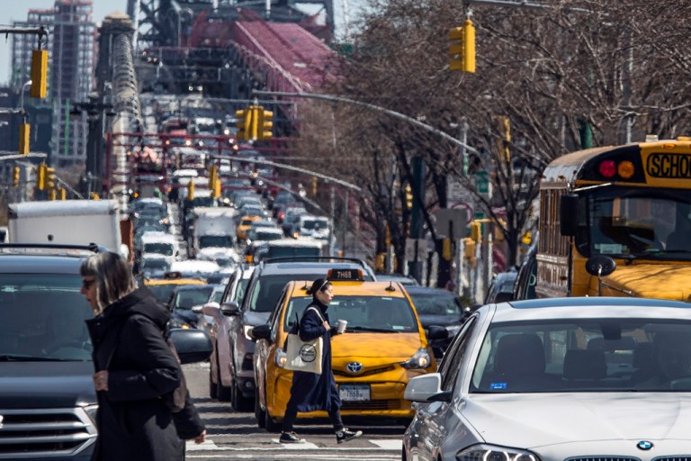 Pedestrians cross Delancey Street as congested traffic from Brooklyn enters Manhattan over the Williamsburg Bridge, March 28, 2019, in New York. The Metropolitan Transportation Authority, the state agency governing New York City transit, formally recognized the Governor's indefinite suspension of a revenue-generating vehicle toll, voting yes on a resolution to delay the implementation of $16.5 billion in subway and bus projects.