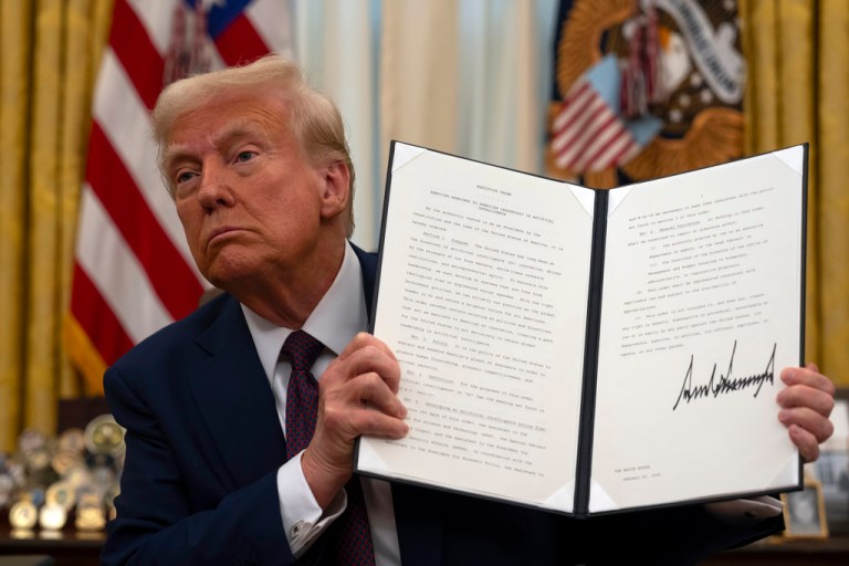 President Donald Trump holds up a signed executive order.