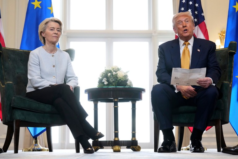 President Donald Trump reads from a paper and European Commission President Ursula von der Leyen listens.