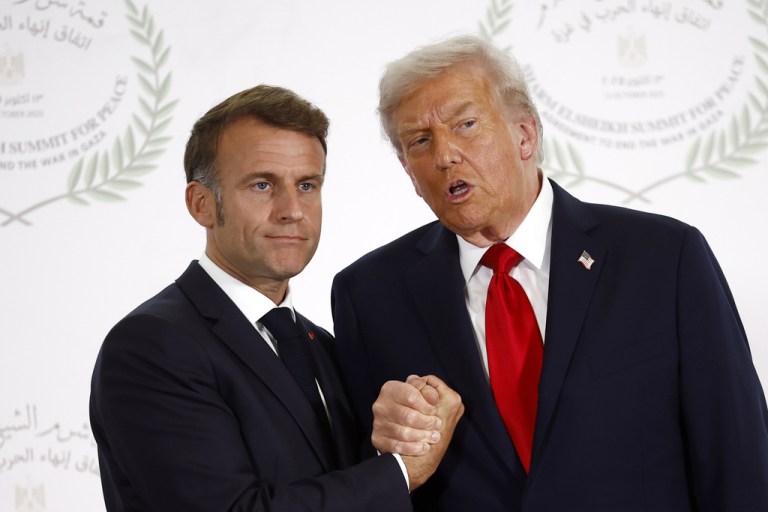 Emmanuel Macron clasps hands with President Donald Trump
