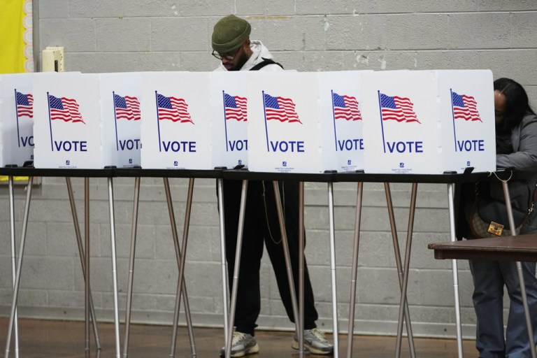 Voters fill out their ballots behind dividers.