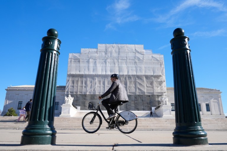 As a person on a bicycle rides past, construction on the front of the U.S. Supreme Court continues Monday, Nov. 24, 2025, in Washington. (AP Photo/Mariam Zuhaib)