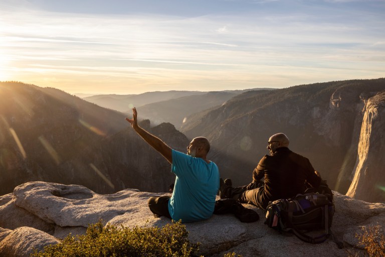People watch a sunset on a rock ledge.