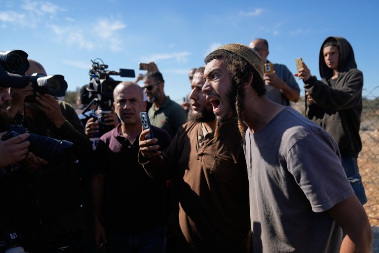 Israeli settlers take pictures of foreign activists and farmers while attempting to disrupt the harvest of olive groves by Palestinian farmers.