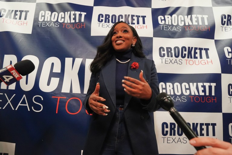 Jasmine Crockett stands in front of a campaign backdrop
