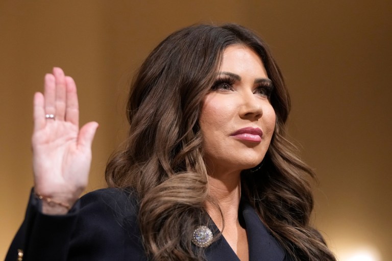 Homeland Security Secretary Kristi Noem raise her arm before the House Committee on Homeland Security.