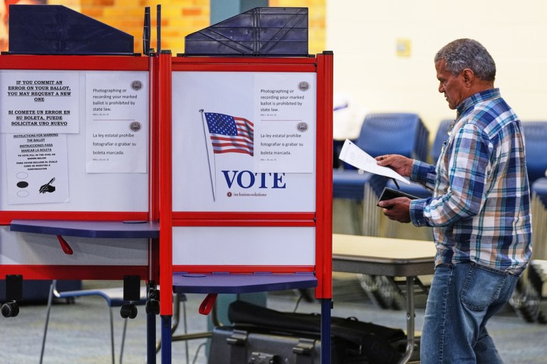 A voter carries his ballot to a booth.