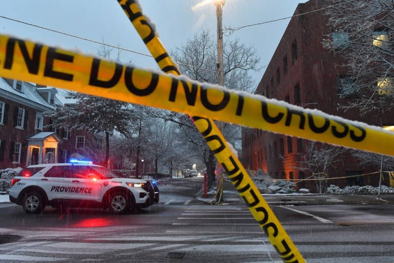 A police vehicle sits at an intersection near crime scene tape at Brown University.
