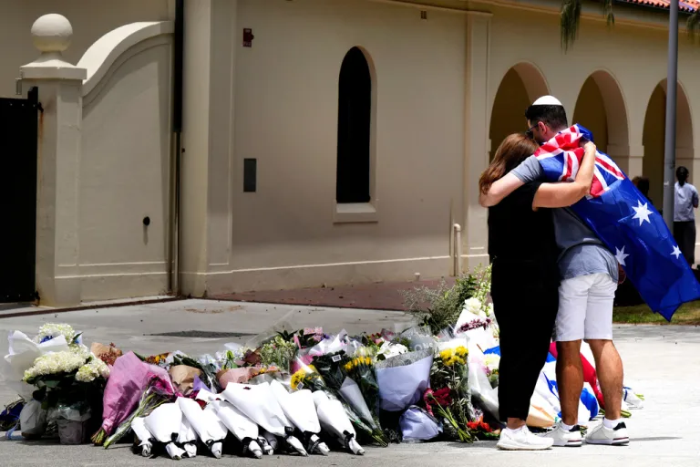 A couple lays flowers at a tribute to shooting victims outside the Bondi Pavilion at Sydney's Bondi Beach.
