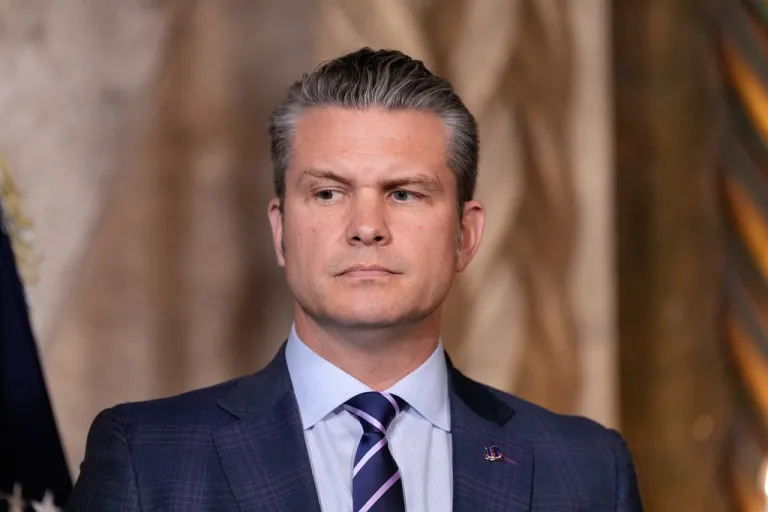 Defense Secretary Pete Hegseth listens as President Donald Trump speaks at his Mar-a-Lago club, Monday, Dec. 22, 2025, in Palm Beach, Fla. (AP Photo/Alex Brandon)