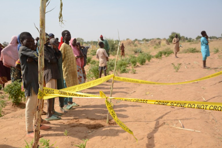 People stand behind crime scene tape at the site of a U.S. airstrike in Northwest, Jabo, Nigeria.