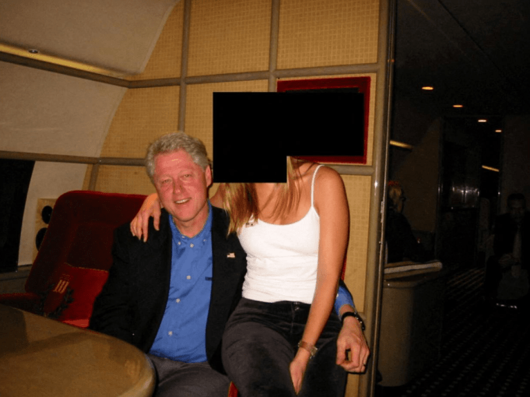 Former President Bill Clinton sits close to an unidentified woman.