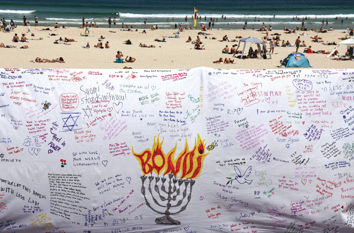 Beachgoers are seen behind a piece of cloth bearing messages from mourners to honor victims of the shooting that took place at the promenade of Bondi Beach in Sydney on Dec. 14. (Photo by David Gray/AFP via Getty Images)