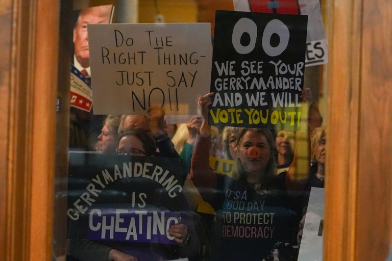 Protesters are seen through a window in the Senate Chamber during dissuasion before a vote to redistrict the state's congressional map.