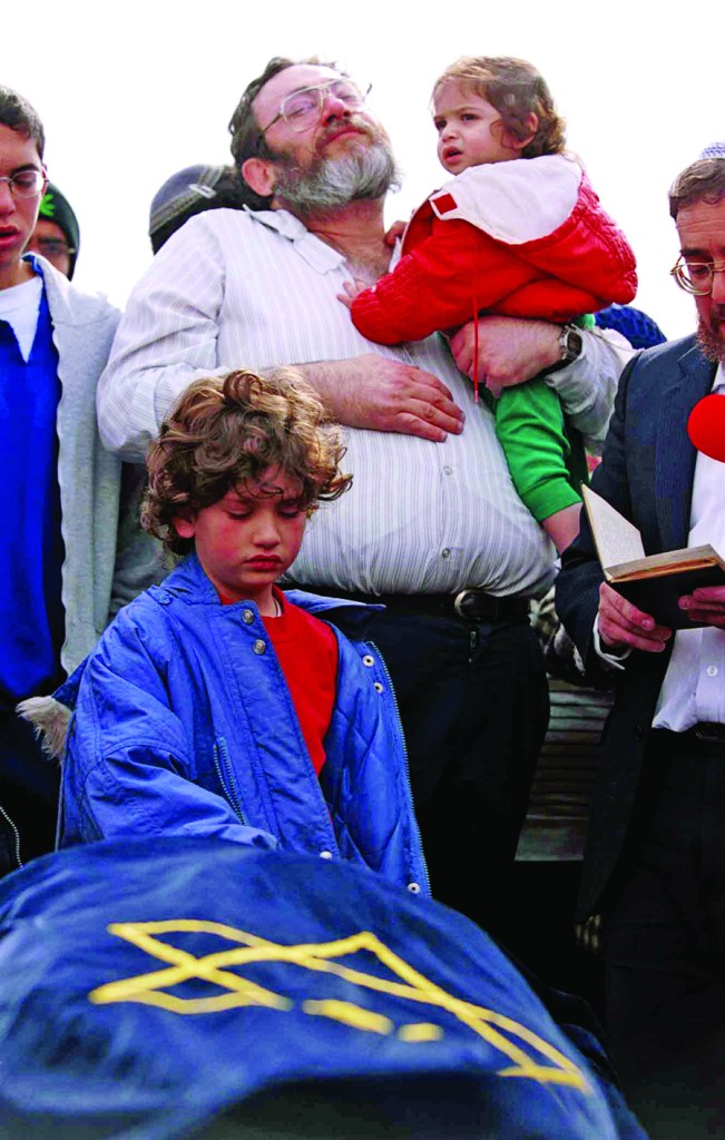 Shlomit Dudevsky, 10, puts her hand on the shroud-covered body of her mother, Hannah Dudevsky, a 39-year-old Jewish woman killed by Palestinian gunmen in a drive-by shooting during the Second Intifada, Dec. 8, 2000. (Nati Shohat/KRT/Newscom)