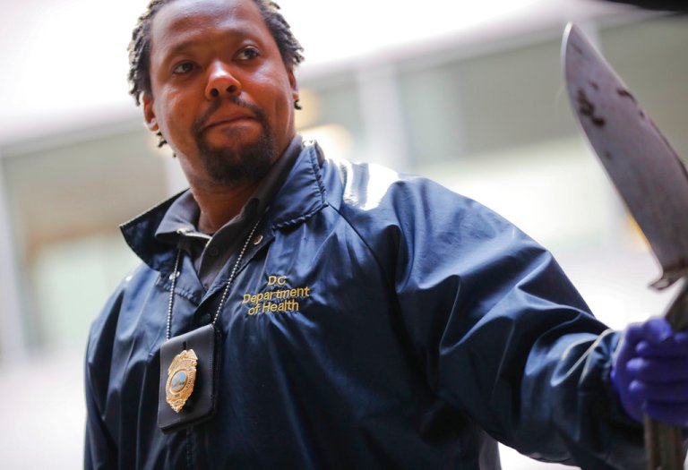 Pest Control Officer Andre Pitman, from the D.C. Department of Health's Rodent Control Division, with his badge and shovel for D.C.'s surging rat population.
