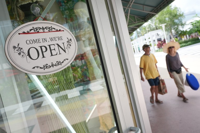 Shoppers walk by a clothing store, Thursday, Sept. 25, 2025, in Miami Beach, Fla.