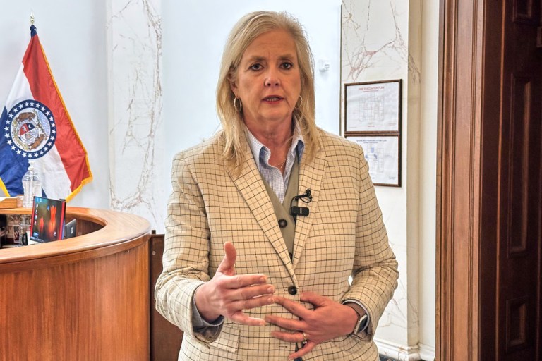 Missouri Attorney General Catherine Hanaway in a cream suit jacket speaks to reporters