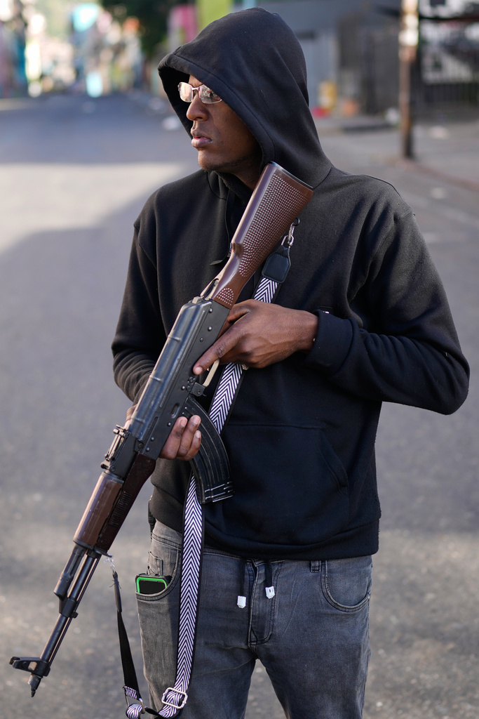 An armed, pro-government civilian stands near shoppers lining up outside a supermarket in Caracas, Venezuela.