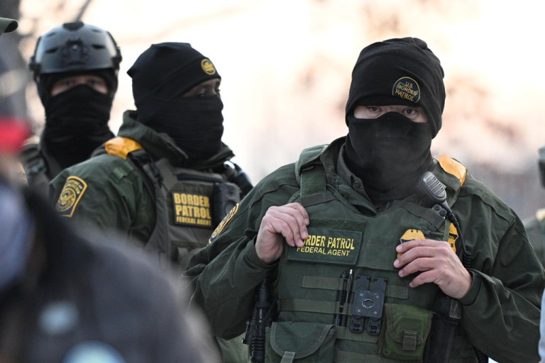 Federal agents look on as protesters gather outside the Bishop Henry Whipple Federal Building in Minneapolis, Minnesota.