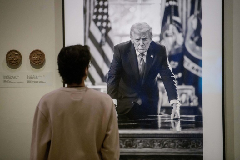 A visitor stops to look at a photograph of President Donald Trump and a short plaque next to it at the Smithsonian's National Portrait Gallery's 