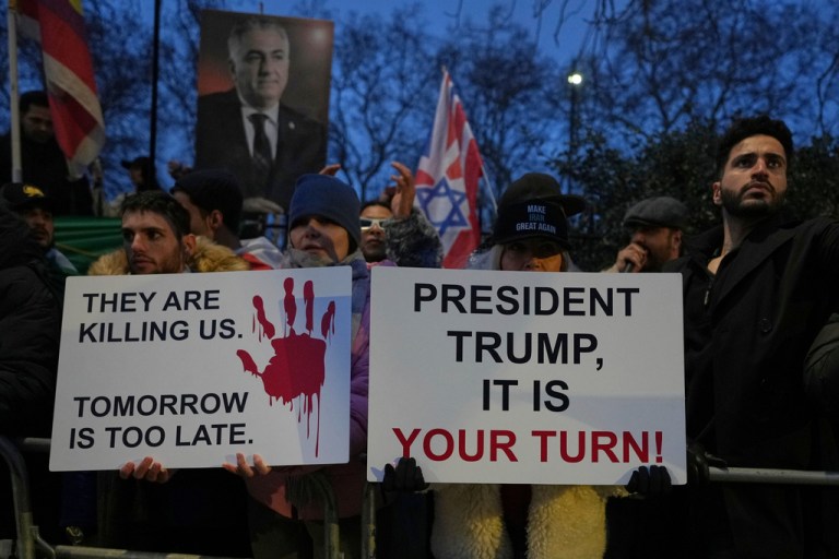 Protesters hold up placards and flags as they demonstrate outside the Iranian Embassy in London, Monday, Jan. 12, 2026.