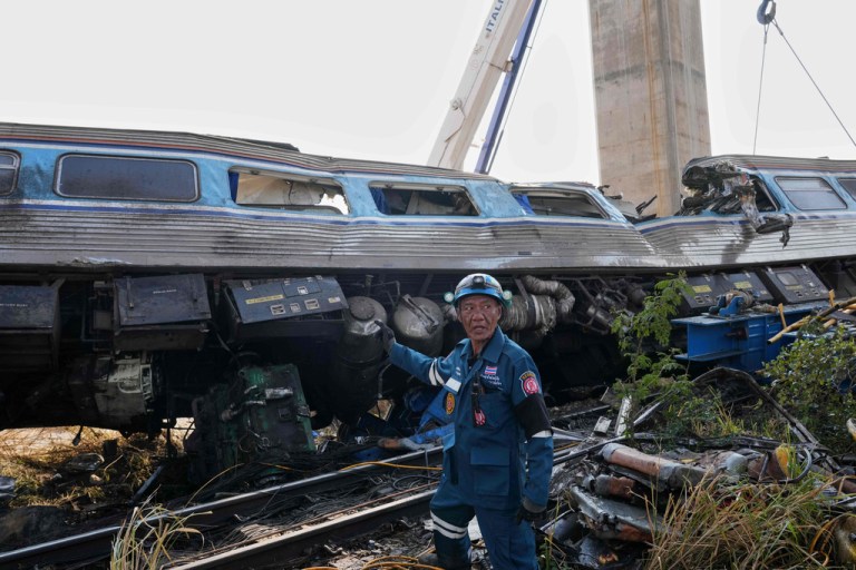 A rescuer stands near the wreckage after a construction crane fell into a passenger train in Nakhon Ratchasima province, Thailand, Wednesday, Jan.14, 2026.