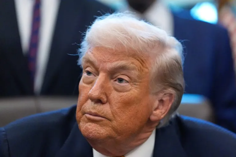 President Donald Trump listens to a question from a reporter after signing a bill that returns whole milk to school cafeterias across the country, in the Oval Office of the White House, Wednesday, Jan. 14, 2026. (AP Photo/Alex Brandon)