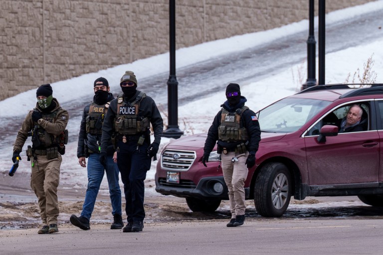 A person looks out of their vehicle as Immigration and Customs Enforcement agents walk away, Thursday, Jan. 15, 2026, in Richfield, Minn. (AP Photo/Adam Gray)