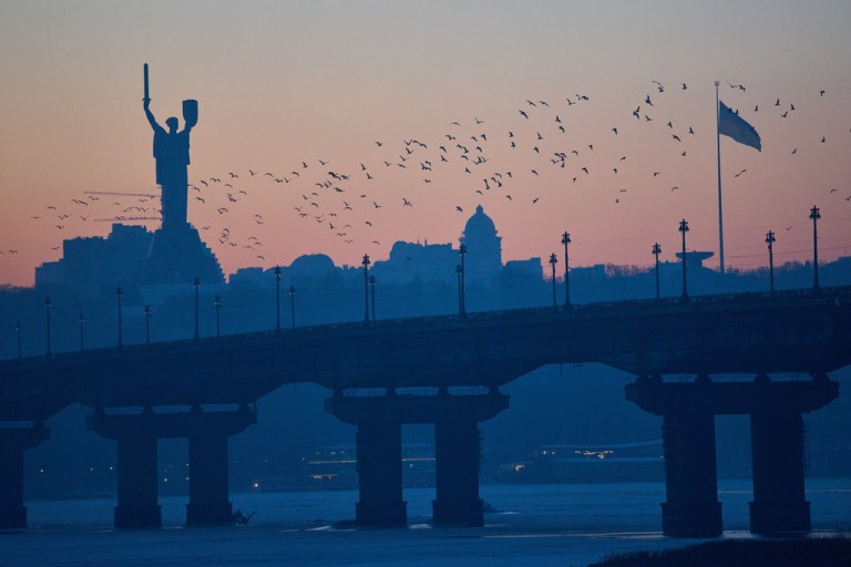 Birds fly over the city at sunset, with the Motherland Monument in the background, in Kyiv, Ukraine, Wednesday, Jan. 21, 2026. (AP Photo/Efrem Lukatsky)