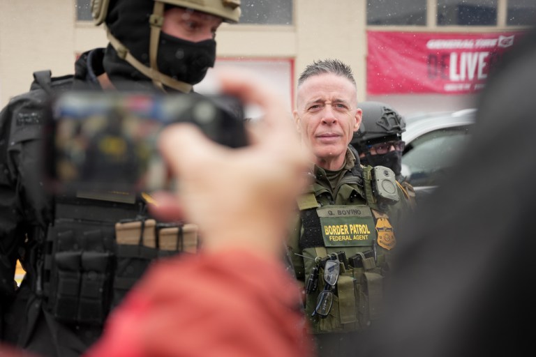 U.S. Border Patrol Cmdr. Gregory Bovino walks with Federal agents outside a convenience store on Wednesday in Minneapolis