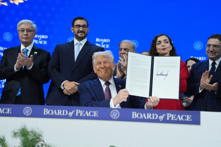President Donald Trump holds up a signed Board of Peace charter.