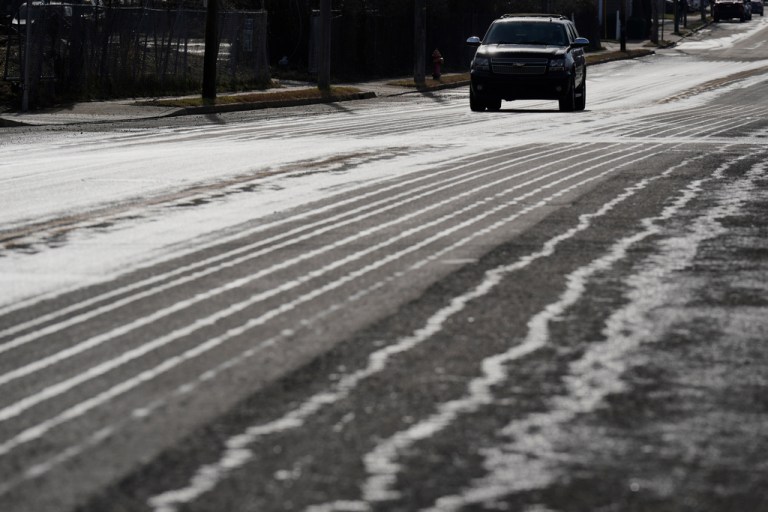 A motorist travels on a road that has been treated with salt brine.