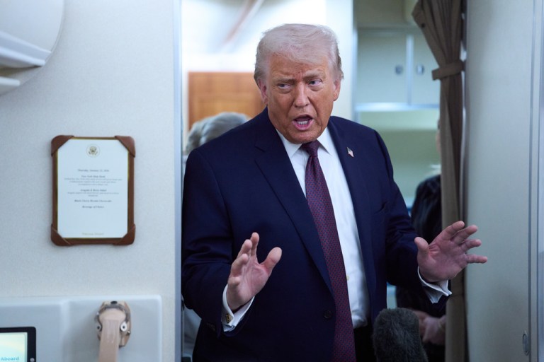 President Donald Trump speaks with reporters aboard Air Force One.