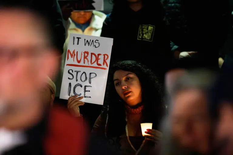 A demonstrator holds a sign at a candlelight vigil during a protest in response to the fatal shooting of 37-year-old Alex Pretti in Minneapolis earlier in the day.