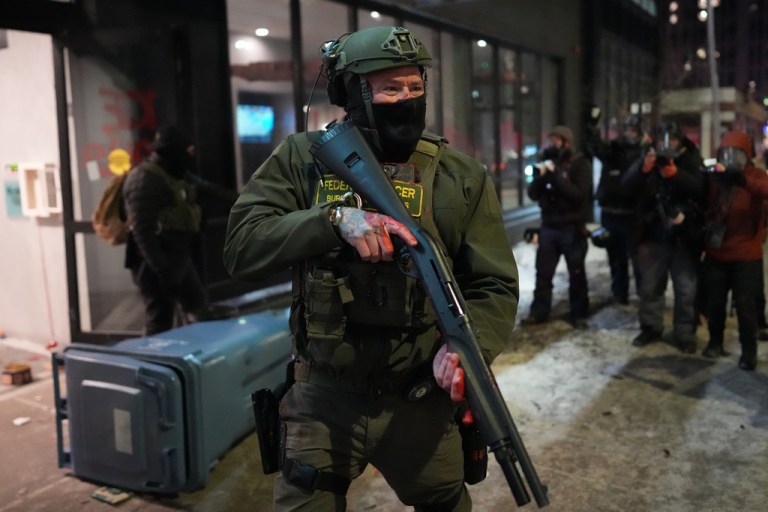 A federal agent stands guard near a hotel during a noise demonstration protest